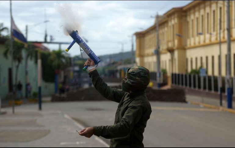 Militante opositor dispara un mortero hechizo. AFP/M. Recinos