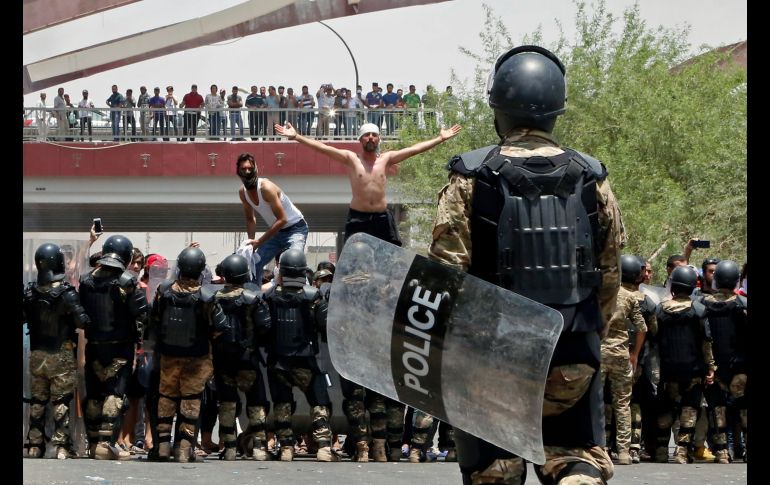 Policías intentan evitar que manifestantes asalten un edificio durante una protesta en Basra, Iraq, realizada para exigir mejores servicios públicos y trabajos. AP