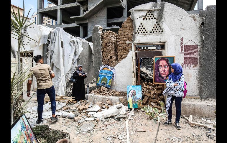 Artistas palestinos exhiben sus obras en el patio de un centro de artes y artesanías, dañado hace dos días durante bombardeos aéreos, en la Ciudad de Gaza. AFP/S. Khatib