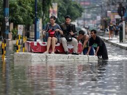 Un grupo de personas se desplaza en una superficie flotante por una vía inundada en Makati, al sur de Manila. EFE/M. Cristino