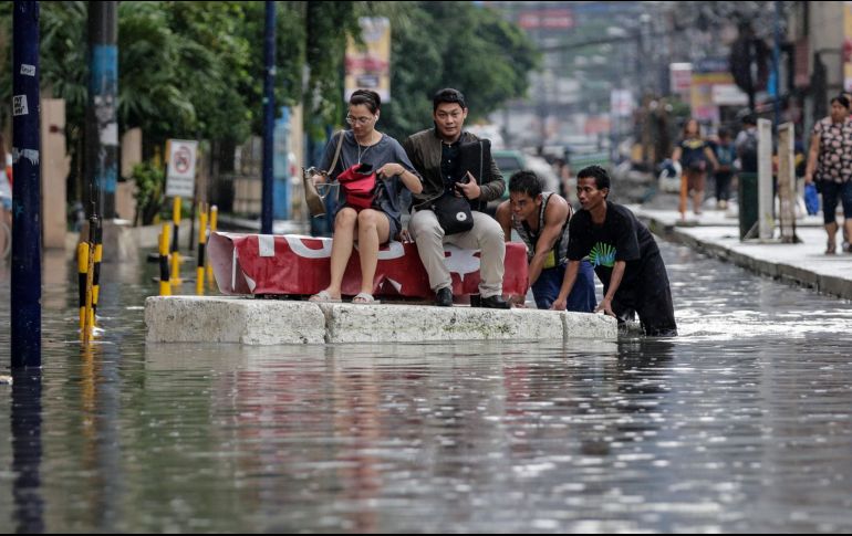 Un grupo de personas se desplaza en una superficie flotante por una vía inundada en Makati, al sur de Manila. EFE/M. Cristino