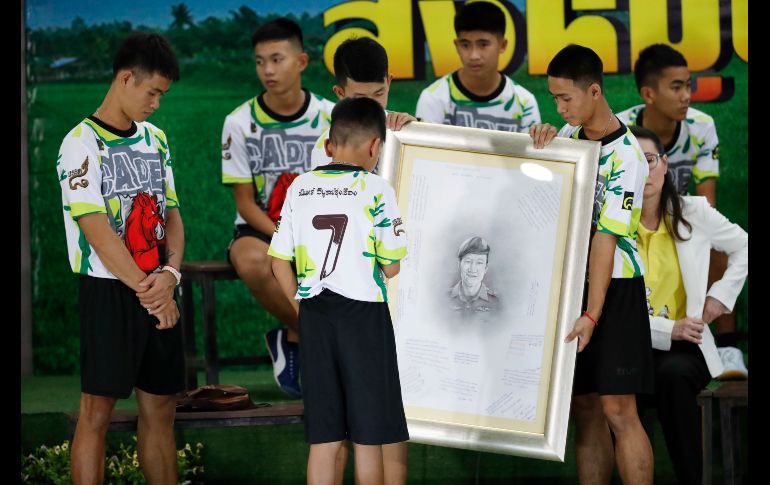 El entrenador Ekkapol Janthawong (i) y algunos de los 12 menores rescatados de la cueva tailandesa rinden homenaje a Saman Gunan, el buzo que falleció en las operaciones de rescate, durante una conferencia de prensa tras salir del hospital en Chiang Rai, Tailandia. AP/V. Thian