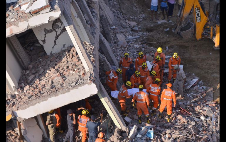 Rescatistas sacan el cuerpo de una víctima entre los escombros de un edificio en Shanberi, India. Al menos cinco personas han muerto al derrumbarse un edificio en construcción sobre otro de menor tamaño. AFP