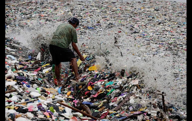 Un hombre busca materiales y objetos reutilizables entre la basura que fue arrastrada hasta la orilla en la bahía de Manila, Filipinas, tras el paso de una tormenta tropical. EFE/ M. Cristino