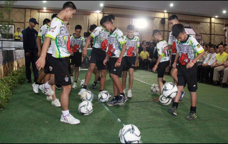Los doce niños y su entrenador rescatados del interior de una cueva en el norte de Tailandia muestran sus habilidades futbolísticas durante su primera aparición pública. EFE