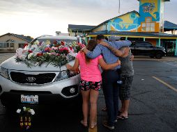 Personas oran en uno de los automóviles pertenecientes a las víctimas del accidente en el lago de Missouri. AP / C. Riedel