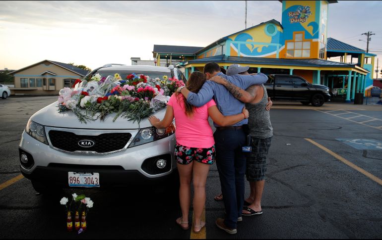 Personas oran en uno de los automóviles pertenecientes a las víctimas del accidente en el lago de Missouri. AP / C. Riedel
