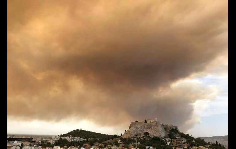 Una pluma de humo torna partes del cielo en color naranja, con la antigua Acrópolis al centro, durante un incendio forestal al oeste de Atenas, Grecia. AP/T. Tongas