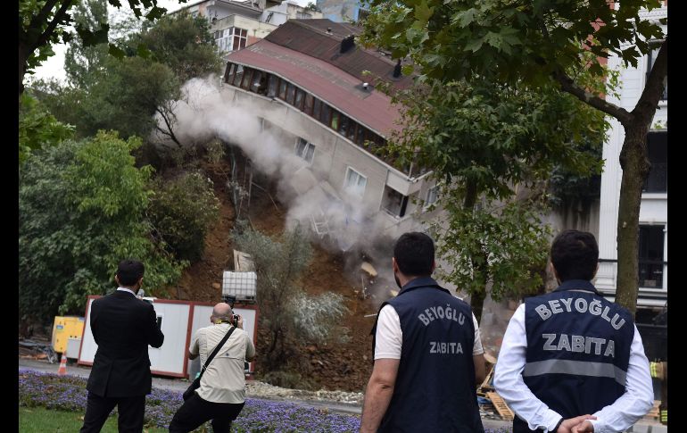 Oficiales municipales se paran junto a un edificio de departamentos de cuatro pisos que colapsó en el distrito Sutluce de Estambul, Turquía, luego de un deslave tras fuertes lluvias. Los habitantes fueron evacuados antes del derrumbe. AFP/Demiroren News Agency