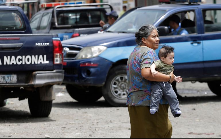 Una mujer carga a un bebé mientras la policía patrulla por calles de Jinotega, Nicaragua. EFE/R. Sura