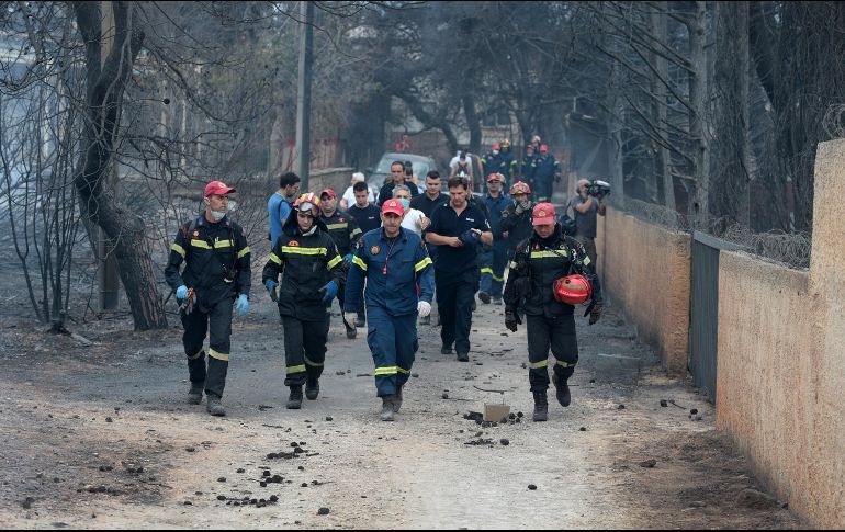 Bomberos permanecen en la zona afectada por los incendios en Argyra Akti. EFE/P. Saitas