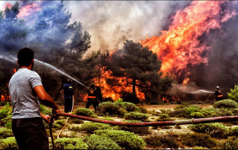 Bomberos intentan sofocar las llamas que se extienden por la costa ateniense. EFE/V. Psomas