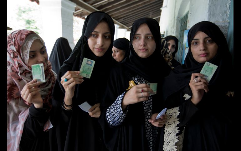 Ciudadanas muestran sus identificaciones mientras esperan para votar en Rawalpindi, Pakistán, en la jornada de elecciones  generales. AP/B.K. Bangash
