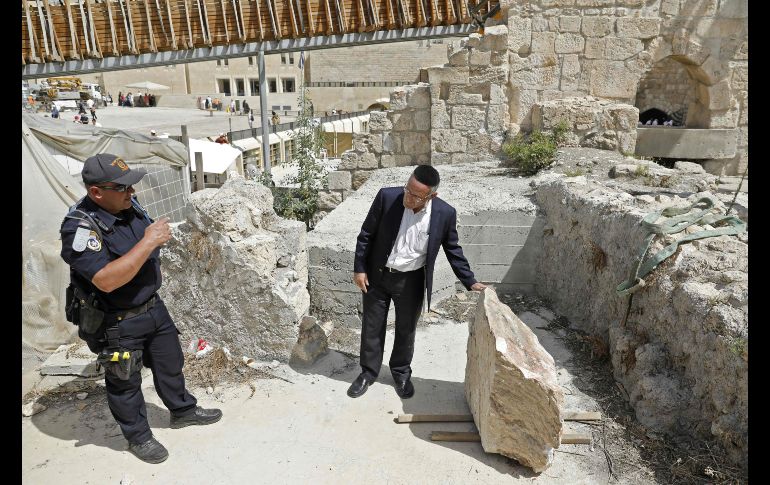 Un integrante de las fuerzas de seguridad israelíes y un judío ortodoxo examinan una piedra que cayó ayer del Muro de las Lamentaciones en Jerusalén, previo a su remoción. AFP/A. Gharabli