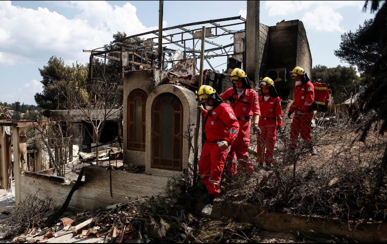 Miembros de la Cruz Roja buscan desaparecidos por las casas tras el incendio registrado en Mati. EFE/y. Kolesidis
