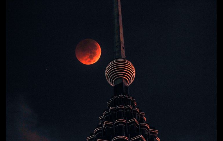 La Luna se ve sobre una de las Torres Petronas en Kuala Lumpur, Malasia.