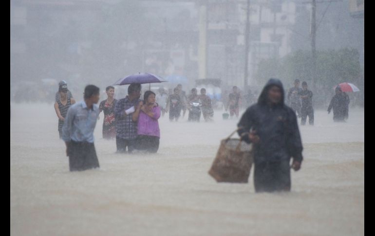 Habitantes caminan en una zona inundada de Bago, Birmania, durante lluvias de la temporada monzónica. AFP/Y. Aung Thu