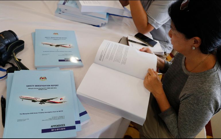 Reporteros que asistieron a la conferencia de prensa leen copias del informe sobre el MH370. AP/V. Thian