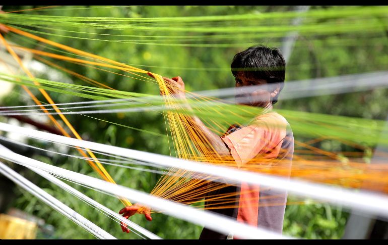 Un trabajador indio construye una cometa de hilo a un lado de la carretera en Jammu, la capital de invierno de Cachemira, India. La cometa se elabora con trozos de cristal, pegamento y colores, y el hilo que la sujeta se unta con huevo para darle más resistencia. EFE/J. Singh