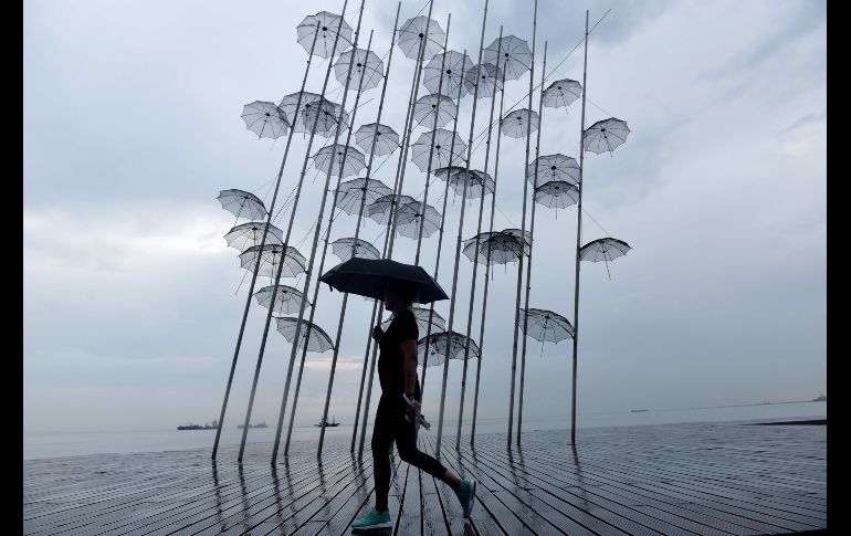 Una mujer que se cubre de la lluvia pasa junto a la escultura 