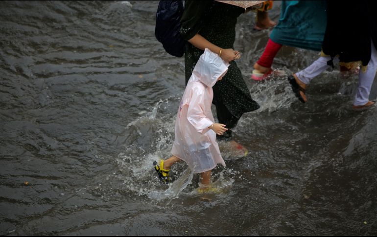 Varias personas caminan por una calle inundada en Calcuta. EFE/P. Adhikary