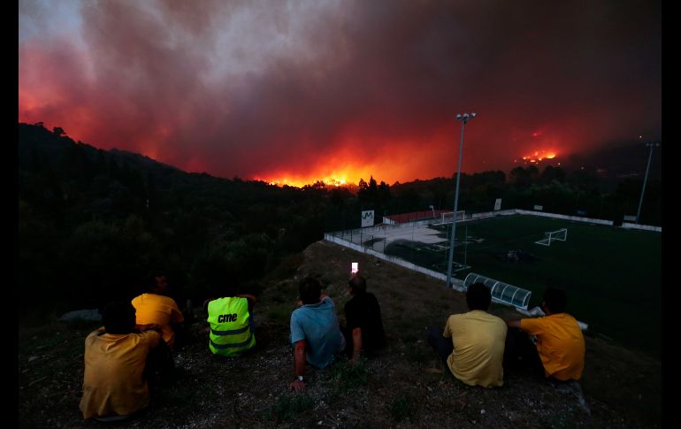 Personas observan un incendio en la población de Brejo, Portugal. Al menos 810 bomberos combaten el incendio forestal en la zona. EFE/F. Farinha