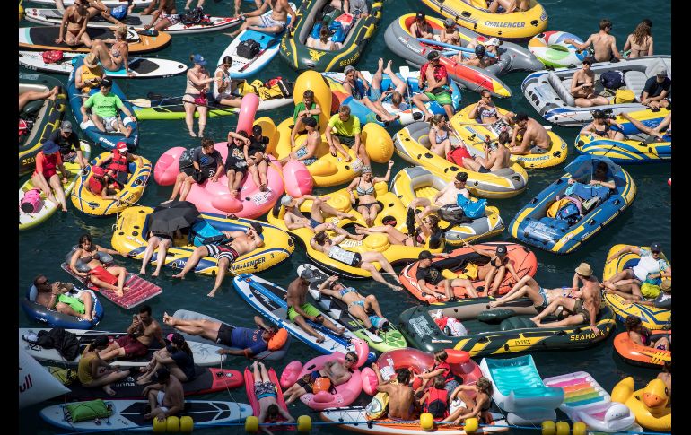 Bañistas se congregan en el lago de Lucerna mientras esperan el inicio de la competición de saltos Red Bull Cliff Diving en Sisikon, Suiza. EFE/ U. Flueeler
