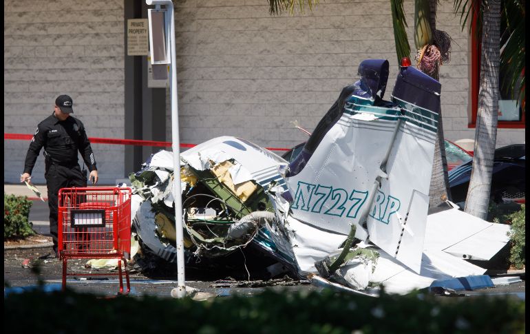 Investigadores observan los restos de una avioneta Cessna que se desplomó hoy en el estacionamiento de un centro comercial en Santa Ana, California, y provocó la muerte de cinco pasajeros. Nadie en tierra resultó herido. EFE/EPA/E. García