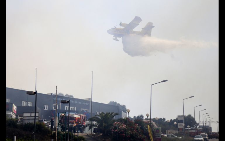 Un helicóptero arroja agua para combatir un incendio en un campamento improvisado en Ajaccio, en la isla francesa de Córcega. AFP/P. Pochard-Casabianca