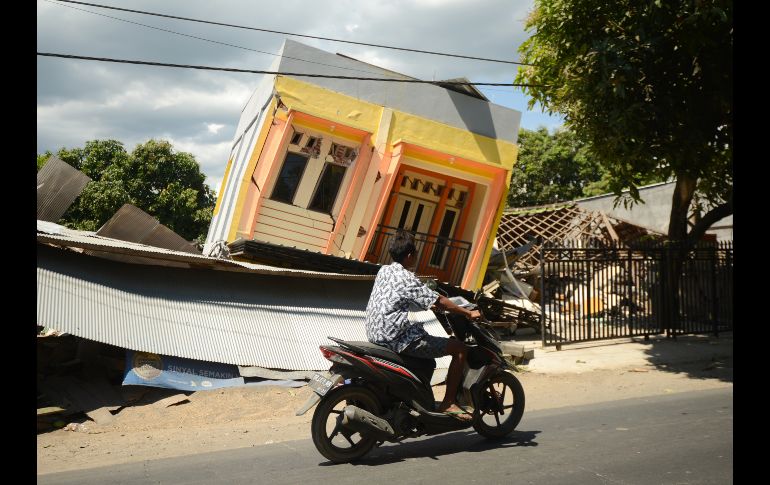 Un hombre pasa por una casa dañada en Sira, en la región indonesia de Lombok, a dos días del sismo que azotó el área y ha dejado 105 muertos. AFP/S. Tumbelaka