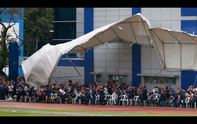 Policías y empleados reaccionan mientras un toldo se levanta por efecto de un helicóptero que realiza un saludo en la ciudad Quezon, Filipinas, en el marco del aniversario del Servicio Policial Nacional. AP/B. Marquez