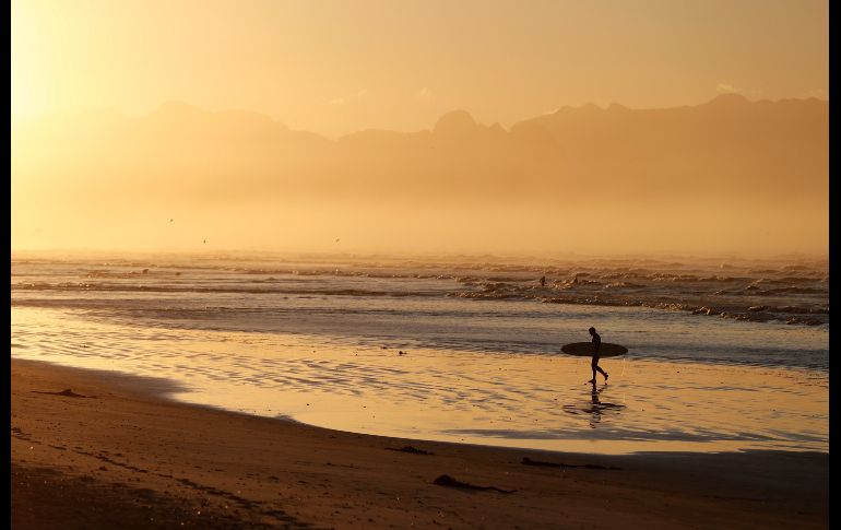 Un surfista pasea al amanecer en la playa Muizenberg en Ciudad del Cabo, Sudáfrica. EFE/N. Bothma