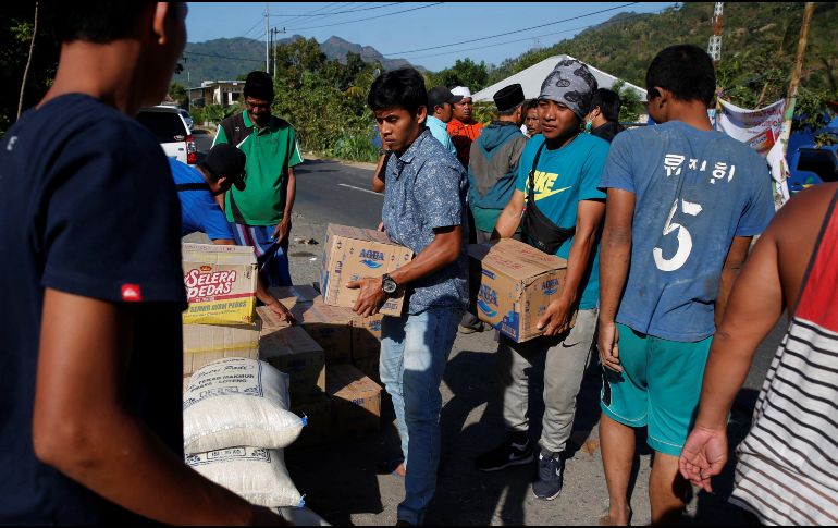 Residentes cargan con cajas de agua para su distribución entre los afectados del terremoto que el domingo sacudió el norte de la isla de Lombok. EFE/A. Weda
