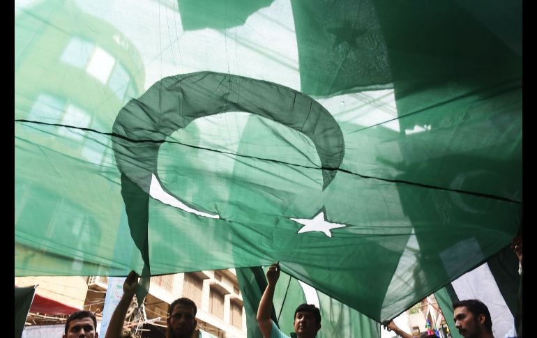 Paquistaníes sostienen una bandera nacional en un puesto en Lahore, como parte de las celebraciones del Día de la Independencia el 14 de agosto. AFP/A. Ali