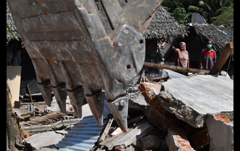 Vecinos observan mientras trabajadores destruyen casas que quedaron estructuralmente dañadas en el sismo de hace una semana en la isla indonesia de Lombok. El balance de muertos suma 387, además de más de 13 mil heridos. AFP/A. Berry