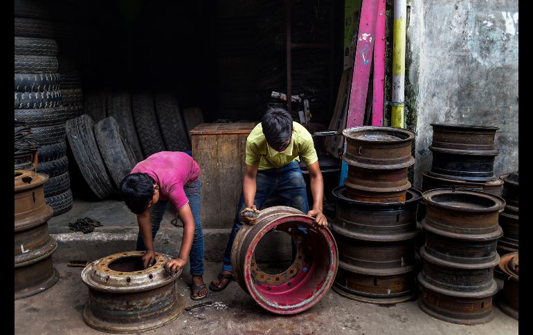Trabajadores limpian óxido de rines usados en Dacca, Bangladesh. AFP/M. Uz Zaman