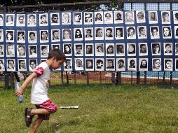 Un niño pasa frente a un mosaico de retratos de desaparecidos durante el Proceso de Reorganización Nacional (1976-1983). AFP/Archivo