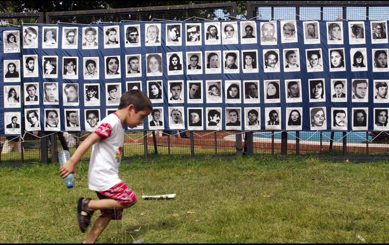 Un niño pasa frente a un mosaico de retratos de desaparecidos durante el Proceso de Reorganización Nacional (1976-1983). AFP/Archivo