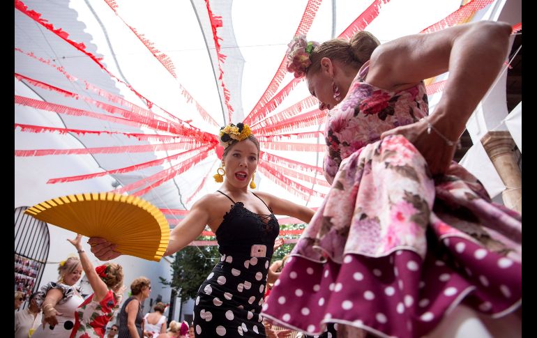 Mujeres vestidas con trajes de flamenca bailan en una calle del centro histórico de Málaga, España, como parte de la feria de la ciudad. EFE/D. Pérez