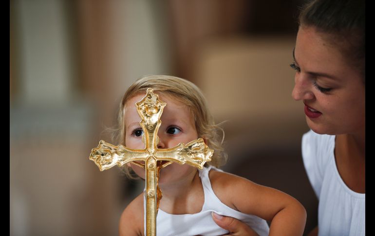 Una niña, sostenida por su madre, besa una cruz en el templo de la Virgen Negra, durante la festividad católica de la Asunción en Letnica, Kosovo. AP/V.  Kryeziu