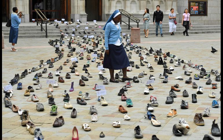 Una religiosa de Zambia camina entre zapatos colocados afuera de la catedral católica de Westminster en Londres, Inglaterra. Los zapatos forman parte de una exposición para promover la campaña de refugiados del Papa Francisco. AFP/B. Stansall