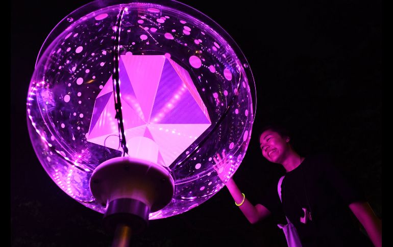 Una visitante toca la instalación de arte 