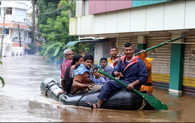 Varias personas cruzan una avenida inundada en una lancha neumática en Kochi, estado de Kerala. EFE/P. Elamakkara