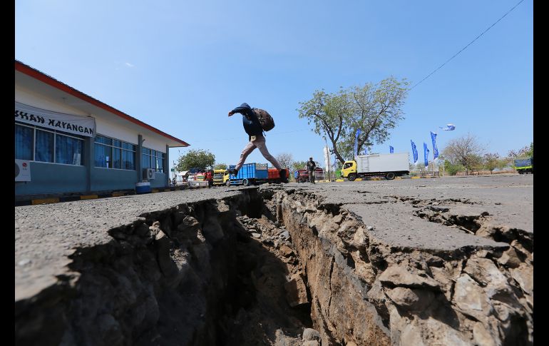 Un hombre salta sobre una grieta en Mataram, en la isla indonesia de Lombok, tras un sismo registrado la víspera. Al menos 14 personas han muerto y 24 han resultado heridas tras el terremoto de magnitud 6.9, lo que eleva el número de fallecidos por temblores en el último mes a casi 490. AFP