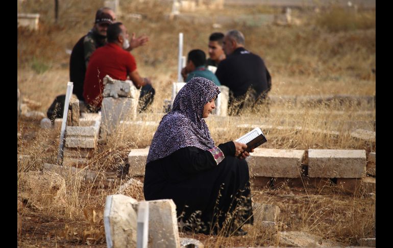 Una mujer lee el Corán cerca de la tumba de un familiar en la ciudad siria de Daraa. AFP/M. Abazeed