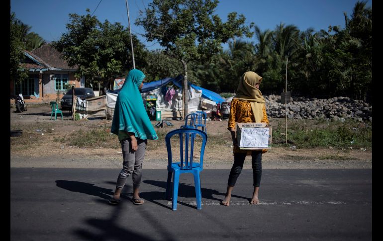 Jóvenes aguardan el paso de conductores para pedir dinero para las víctimas del sismo en Sambelia, en la isla indonesia de Lombok. AFP/F. Dufour