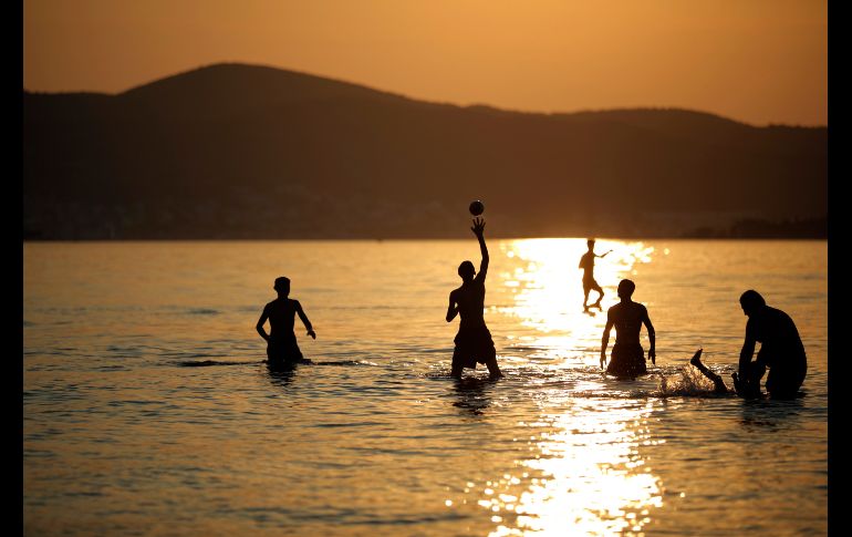 Personas disfrutan el mar durante el atardecer en Izmir, Turquía. AP/E. Tazegul