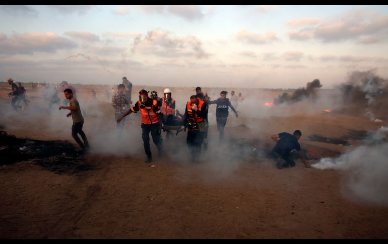Médicos evacuan a un joven herido mientras otros huyen del gas lacrimógeno lanzado por tropas israelíes cerca de la frontera de la Franja de Gaza, en una de las protestas semanales de palestinos. AP/A. Hana