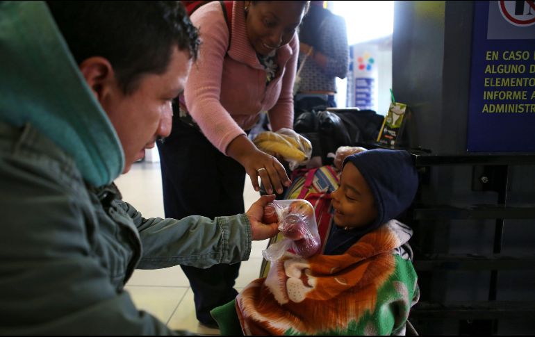 Un pariente ofrece fruta a un niño después de que viajó durante 20 horas desde Tumbes, al noroeste de Perú, en la terminal de autobuses en el norte de Lima. AFP/T. Bizca