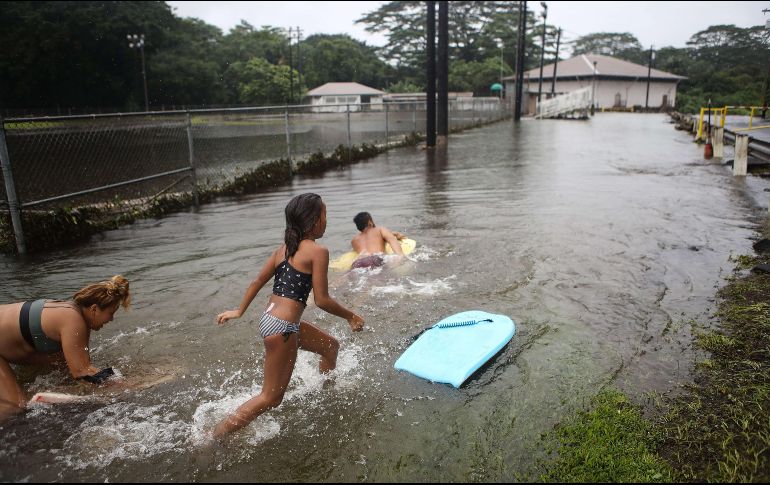 Hawaianos juegan en el agua luego de que se registraron inundaciones en algunos campos tras el paso de “Lane”. AFP / M. Tama